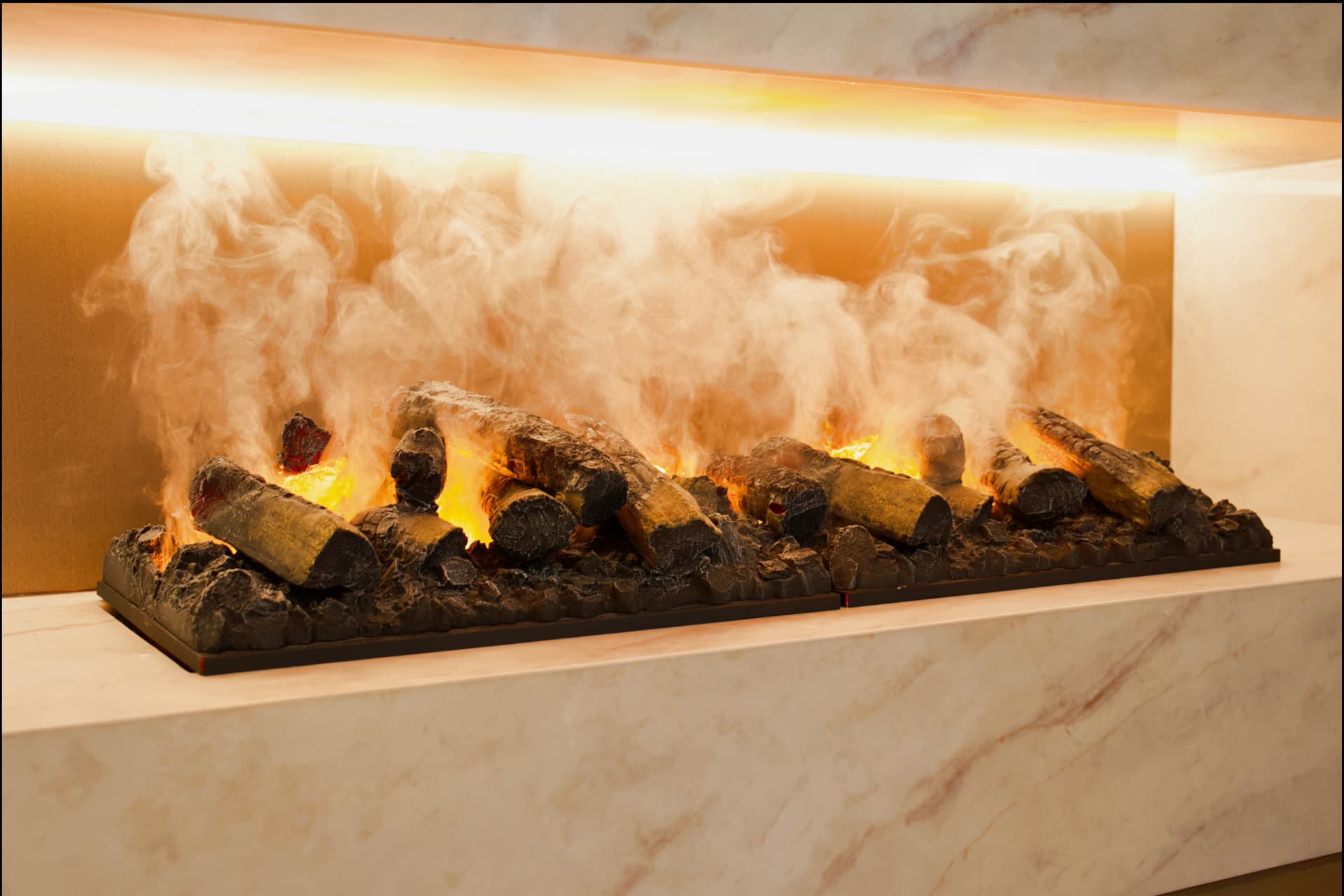 Close view of the linear fireplace firebox with log set and cove lighting